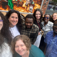 Nicole Cohen, Naomi Popeski, James Idowu, Doreen Rabi, Marie Claire Uwamahoro, Stacy Kozak, Fobete Dingha, and Julie Babione gather for a post-lunch picture at the Lazy Loaf & Kettle in Calgary, Canada.