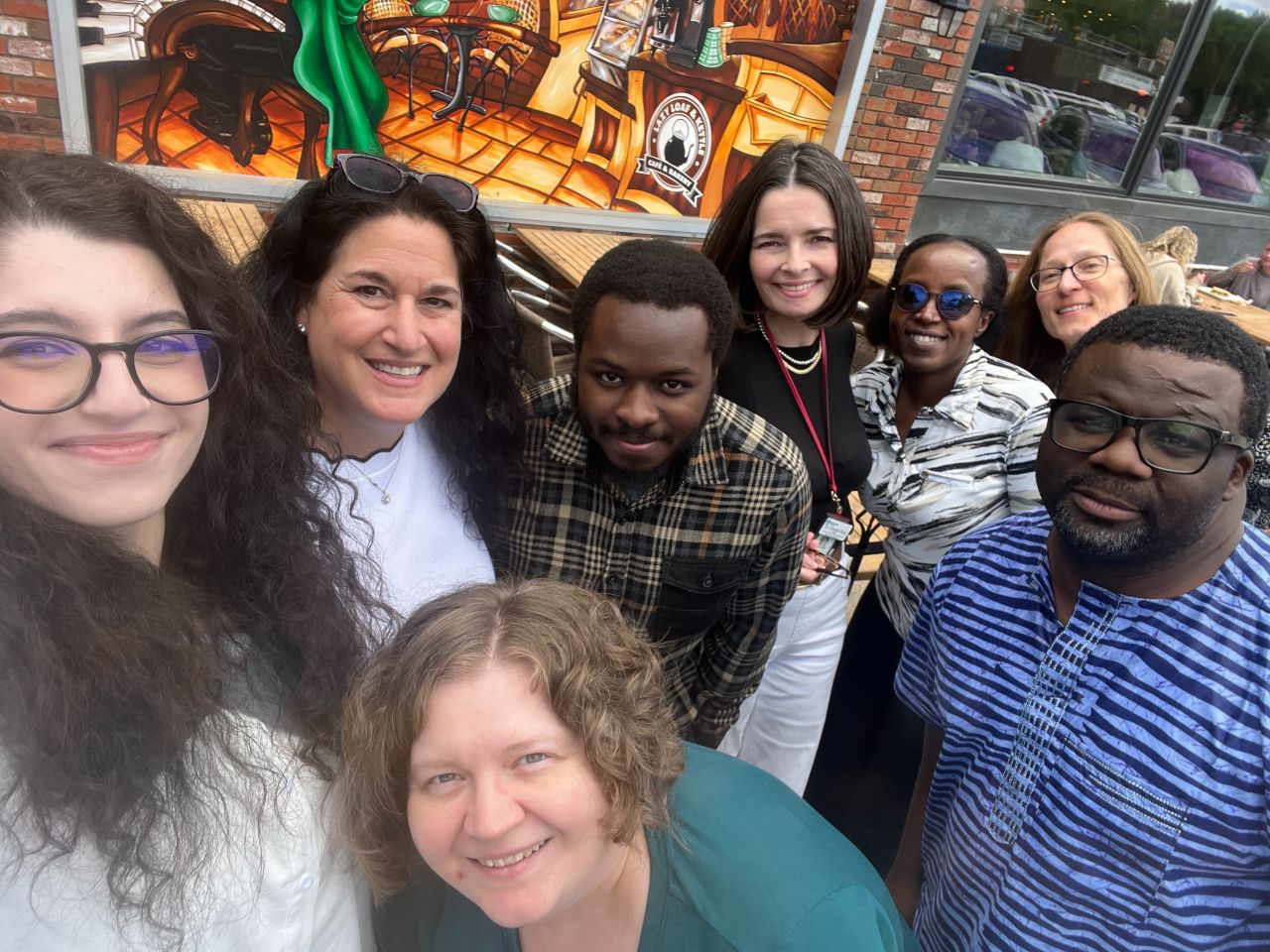Nicole Cohen, Naomi Popeski, James Idowu, Doreen Rabi, Marie Claire Uwamahoro, Stacy Kozak, Fobete Dingha, and Julie Babione gather for a post-lunch picture at the Lazy Loaf & Kettle in Calgary, Canada.
