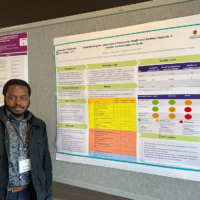 James Idowu standing in front of his poster as presented at CAHSPR 2026
